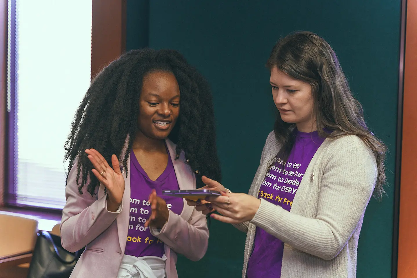 Two staff members collaborate around an iPad.